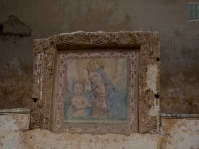 La Vergine, avvolta da un mantello azzurro, indossa una corona dorata e sorveglia con sguardo amorevole il messia, il quale tra le mani coccola un cardellino